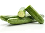 Three cucumbers piled on a white surface; one is cut, showing pale green flesh and seeds in the center.
